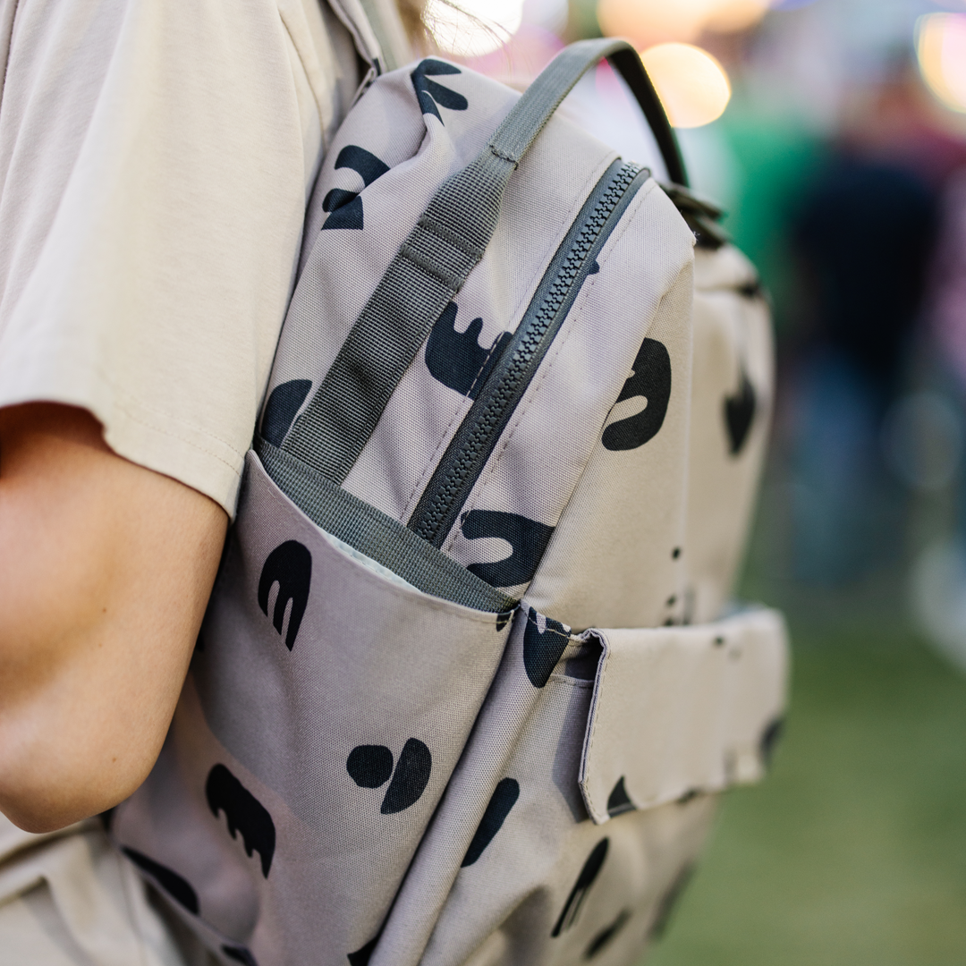 Inside view of the Little Unicorn Red Rovr Mini Roo Backpack in Truffle Doodle reveals smart space for essentials as a kids travel backpack.