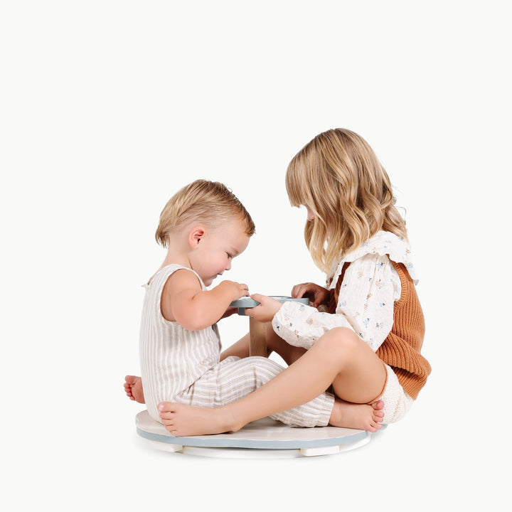 Two sisters play together near the Gathre Sit and Spin, sharing a moment of imaginative fun