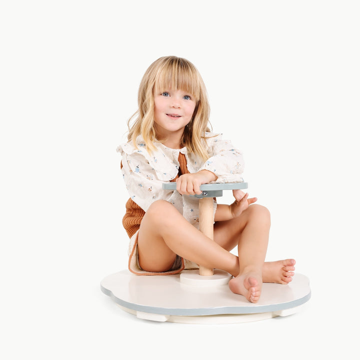 Little girl grips the handle of Gathre's Sit and Spin, ready to twirl on the play mat