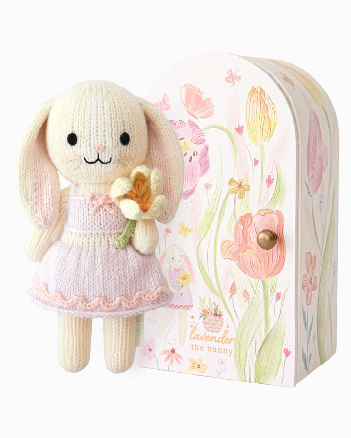 Cuddle + Kind Tiny Lavender the Bunny hand-knit doll holding a tulip in a lavender outfit