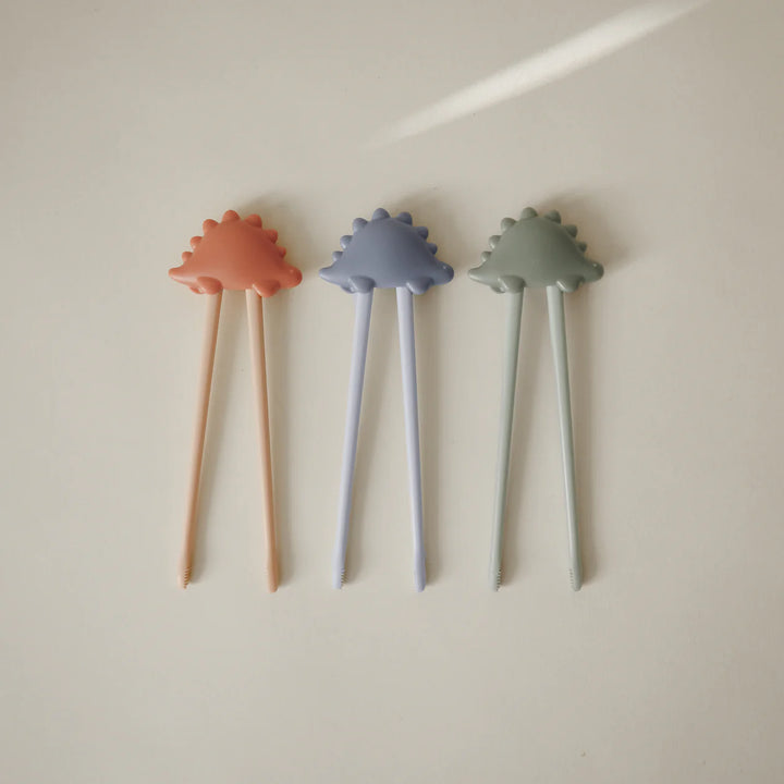 Toddler using Mushie Training Chopsticks at mealtime - child developing fine motor skills with learner chopstick set