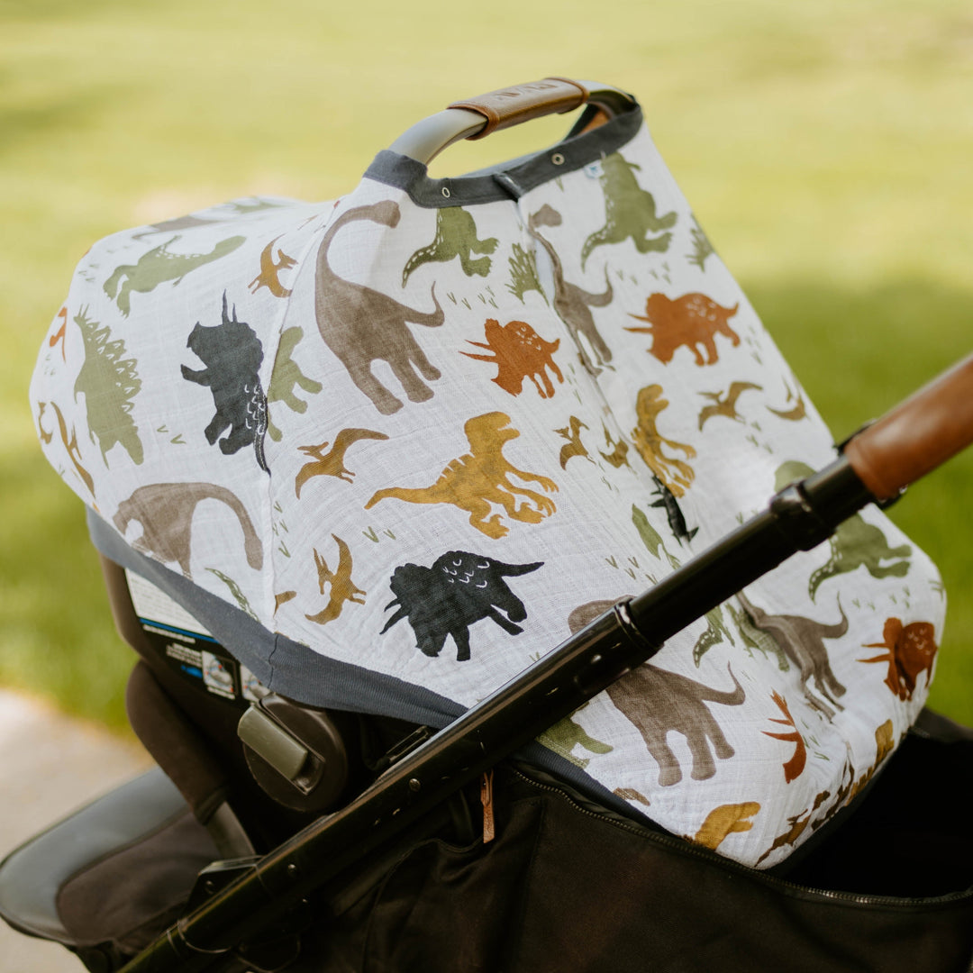 Charming dinosaur pattern featured on the Little Unicorn Cotton Muslin Car Seat Canopy - Dino Friends, an adorable car seat accessory.