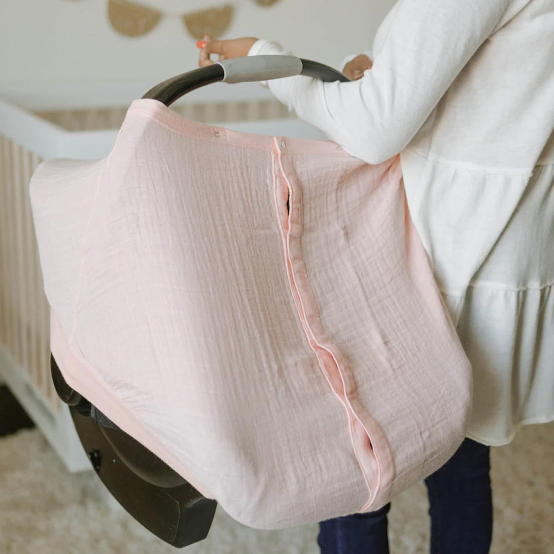 Lifestyle image showing the Little Unicorn Cotton Muslin Car Seat Canopy - Light Pink in use, an essential for baby car seat style.