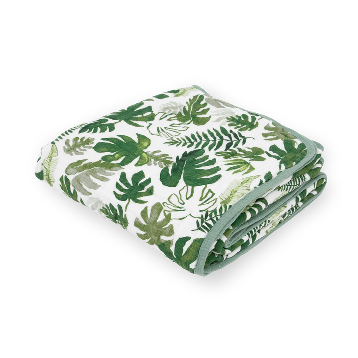 Little Unicorn Original Cotton Muslin Quilt - Tropical Leaf neatly folded, a soft baby blanket with lush tropical-inspired patterns.