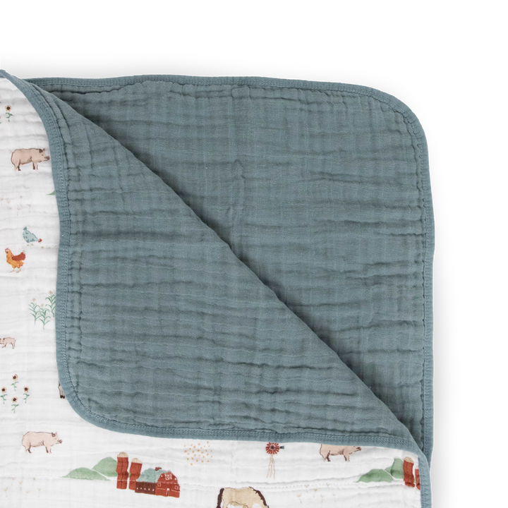 The Little Unicorn Original Cotton Muslin Quilt - Farmyard displayed flat, showcasing its colorful farm print muslin blanket design.