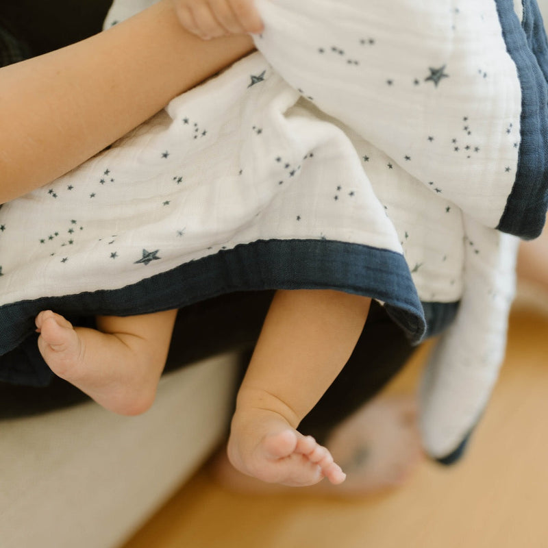 Little Unicorn Cotton Muslin Baby Quilt - Shooting Stars draped across a crib, offering a soft and stylish muslin quilt for little ones.