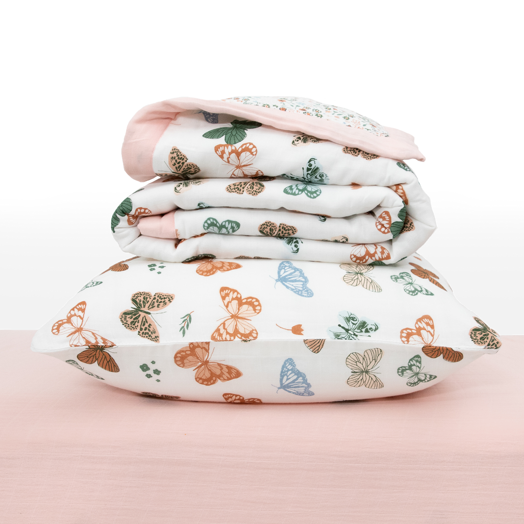 Flat lay of Little Unicorn Cotton Muslin Toddler Bedding 3 Piece Set - Butterflies, breathable baby crib bedding set.