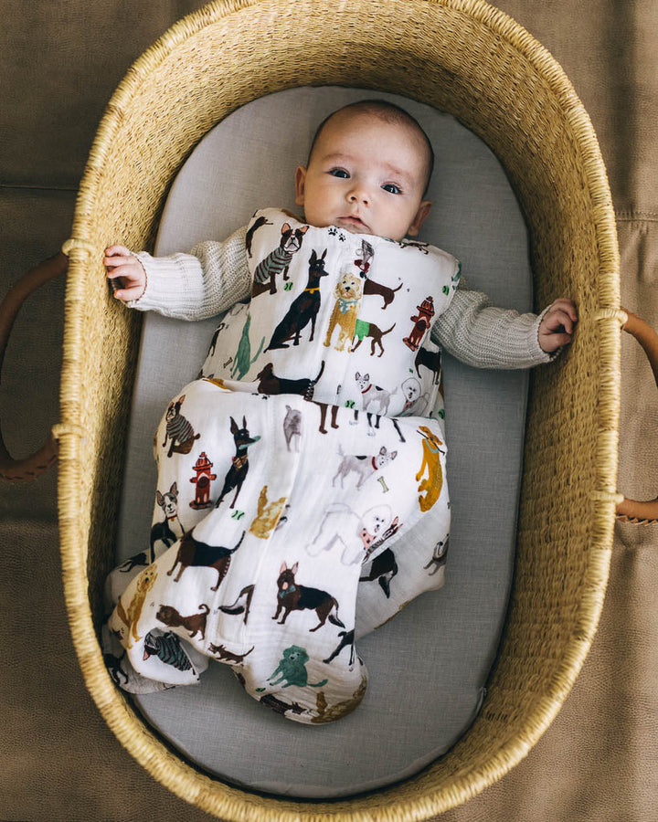 Lifestyle image of Little Unicorn Cotton Muslin Sleep Bag - Woof draped on a crib, offering soft sleep bags for babies.