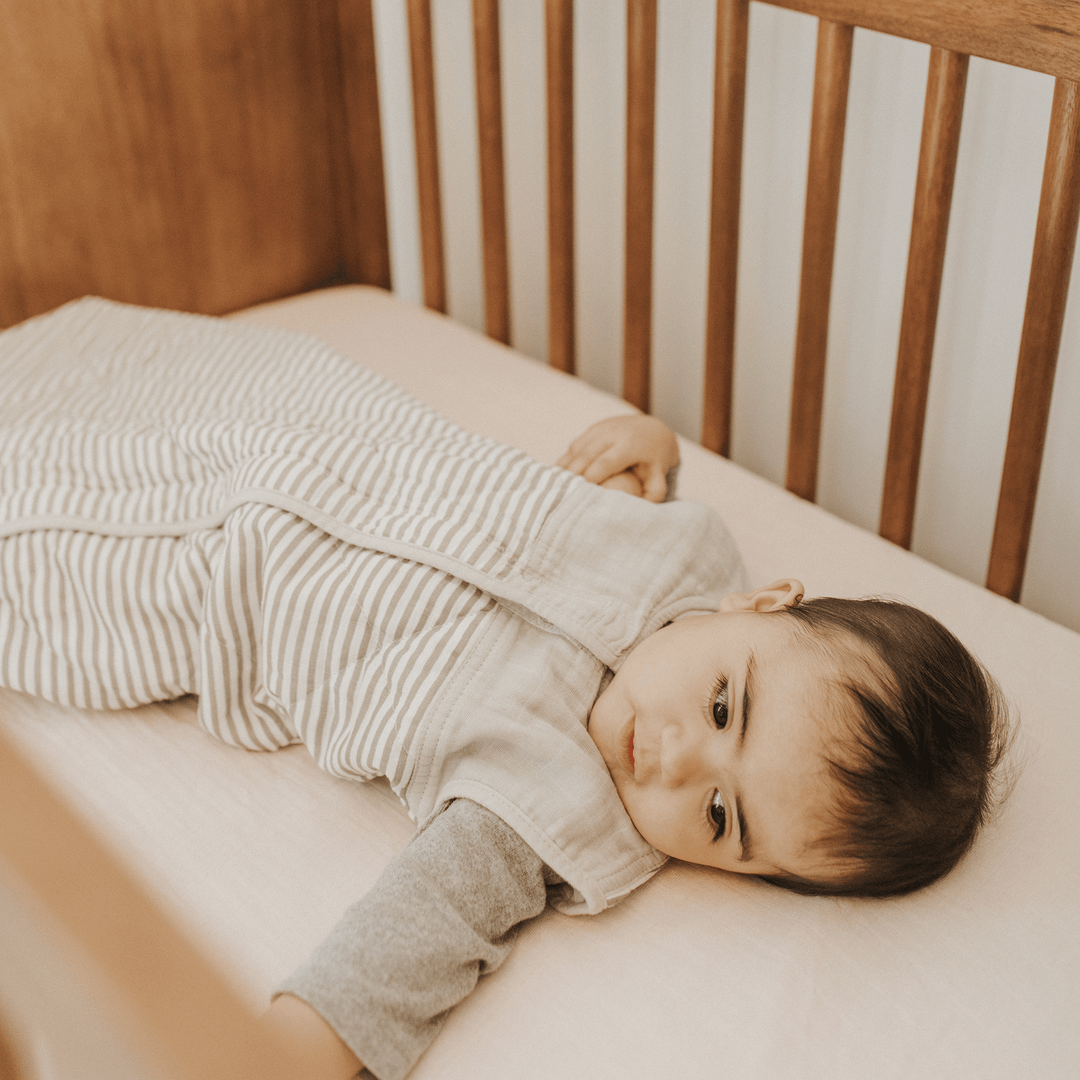 Styled nursery view of Little Unicorn Cotton Muslin Quilted Sleep Bag - Grey Stripe, perfect sleeping bag baby for bedtime.