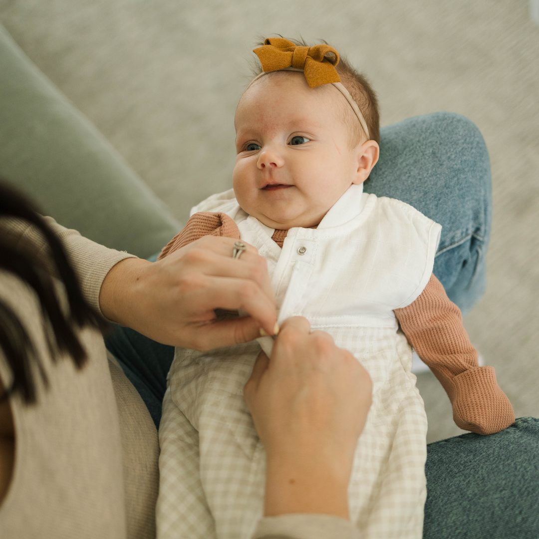 Styled crib image showing Little Unicorn Cotton Muslin Quilted Sleep Bag - Tan Gingham, ideal sleeping bag baby for nighttime.