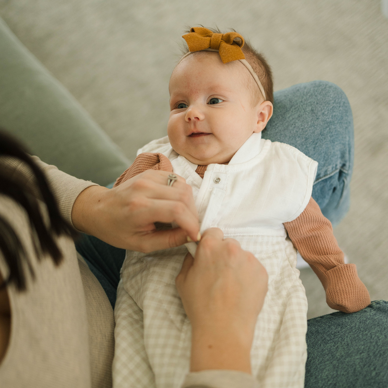Styled crib image showing Little Unicorn Cotton Muslin Quilted Sleep Bag - Tan Gingham, ideal sleeping bag baby for nighttime.
