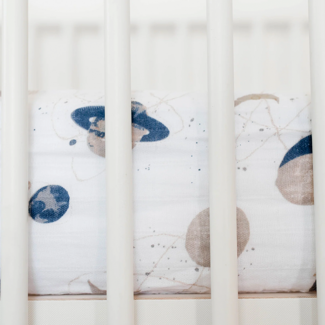 Little Unicorn Cotton Muslin Crib Sheet - Planetary styled on mattress, cozy and fun crib bed sheets for little dreamers.