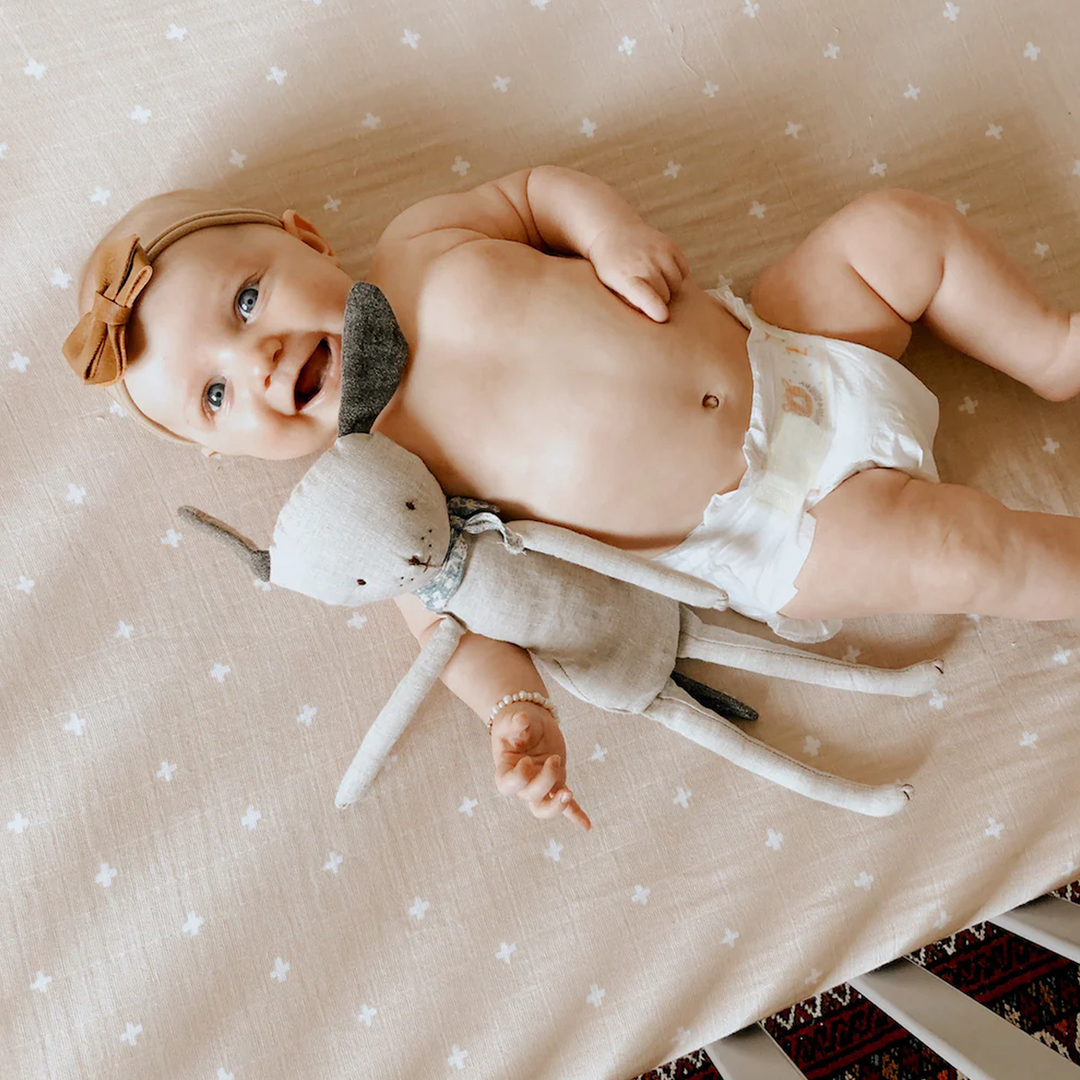 Stylish nursery setup featuring Little Unicorn Cotton Muslin Crib Sheet - Taupe Cross, high-quality organic cotton crib sheets.