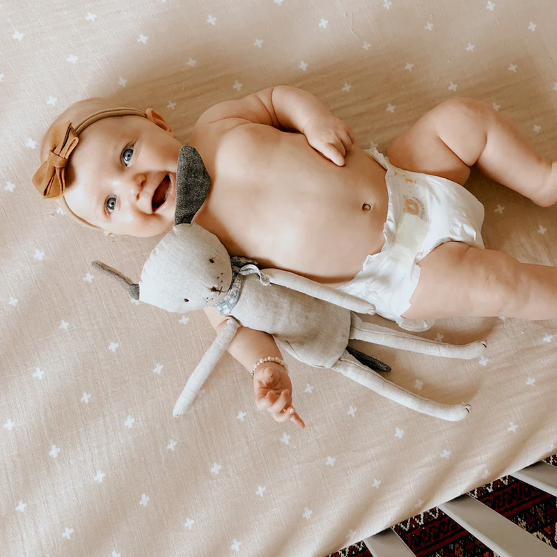 Stylish nursery setup featuring Little Unicorn Cotton Muslin Crib Sheet - Taupe Cross, high-quality organic cotton crib sheets.