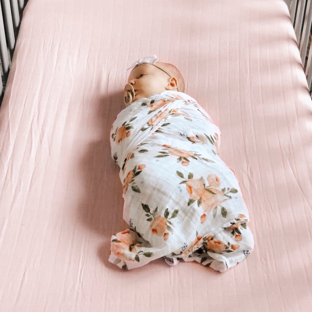 Little Unicorn Light Pink Cotton Muslin Crib Sheet styled on crib, one of the best crib sheets for newborns
