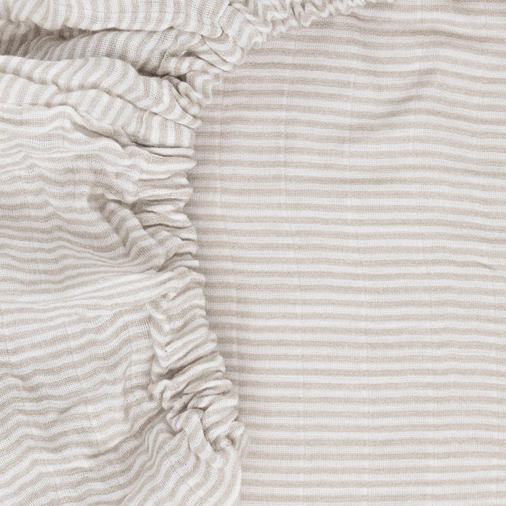 Little Unicorn Sand Stripe Organic Cotton Muslin Crib Sheet styled on crib mattress, one of the best crib sheets for babies