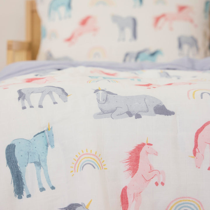 Layered display showing Little Unicorn Cotton Muslin Toddler Comforter - Unicorns, baby swaddle for gentle sleep.