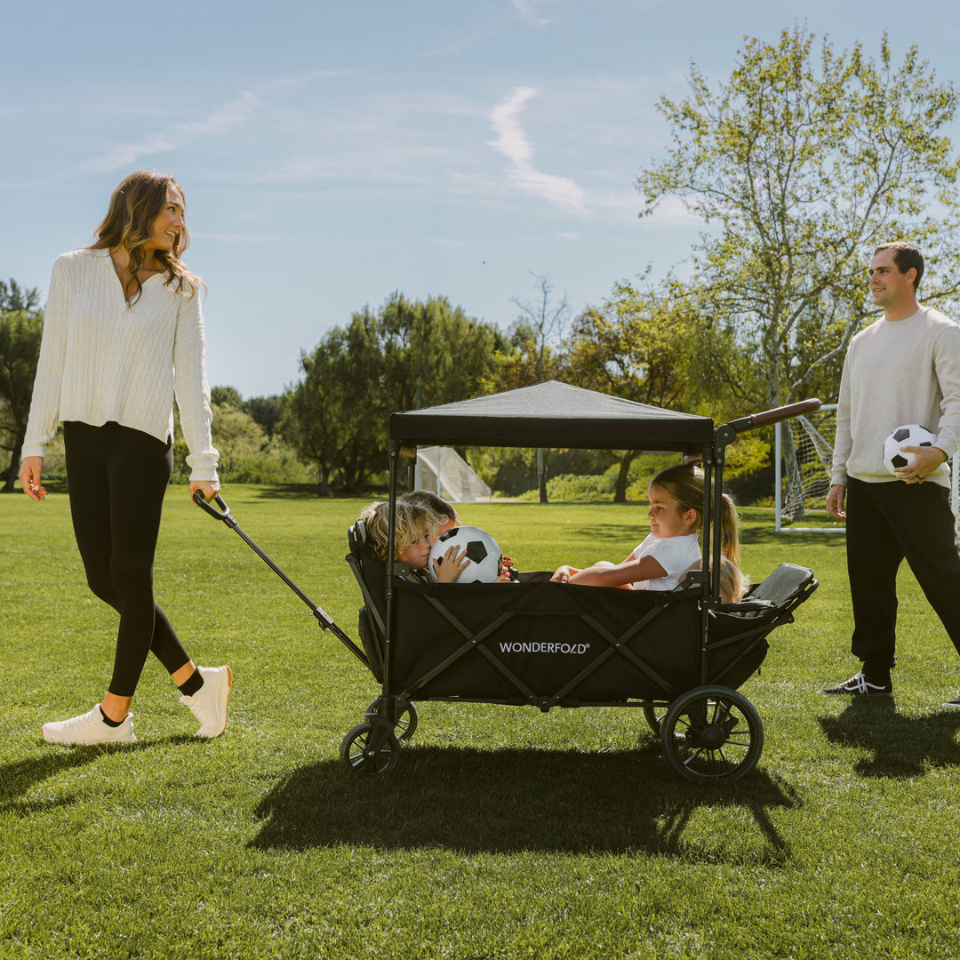 Parents pushing the Wonderfold X4R Quad Stroller Wagon, a quad stroller for park and game days