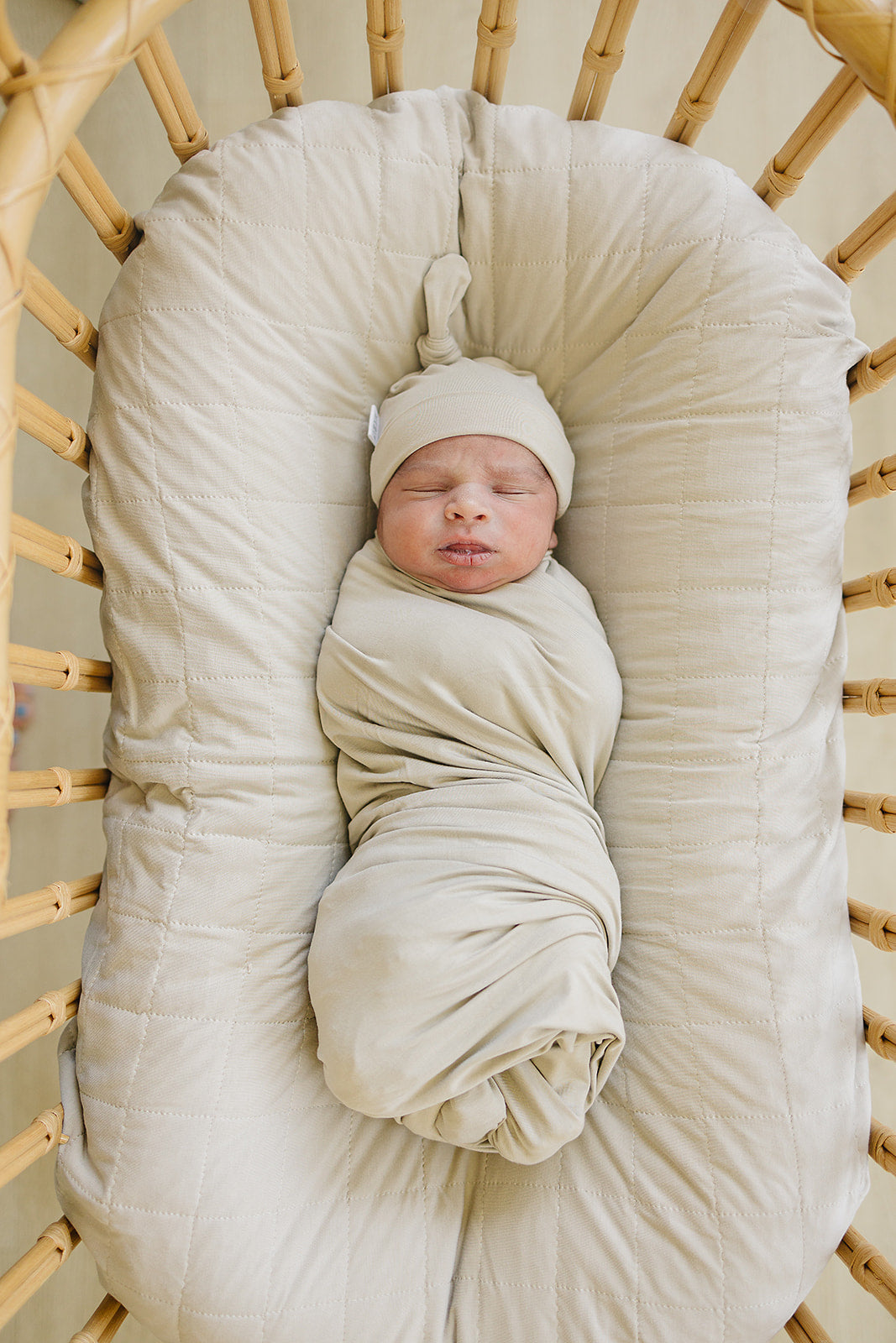 Wrapped around a sleeping newborn, the Oatmeal Bamboo Stretch Swaddle from Mebie Baby.