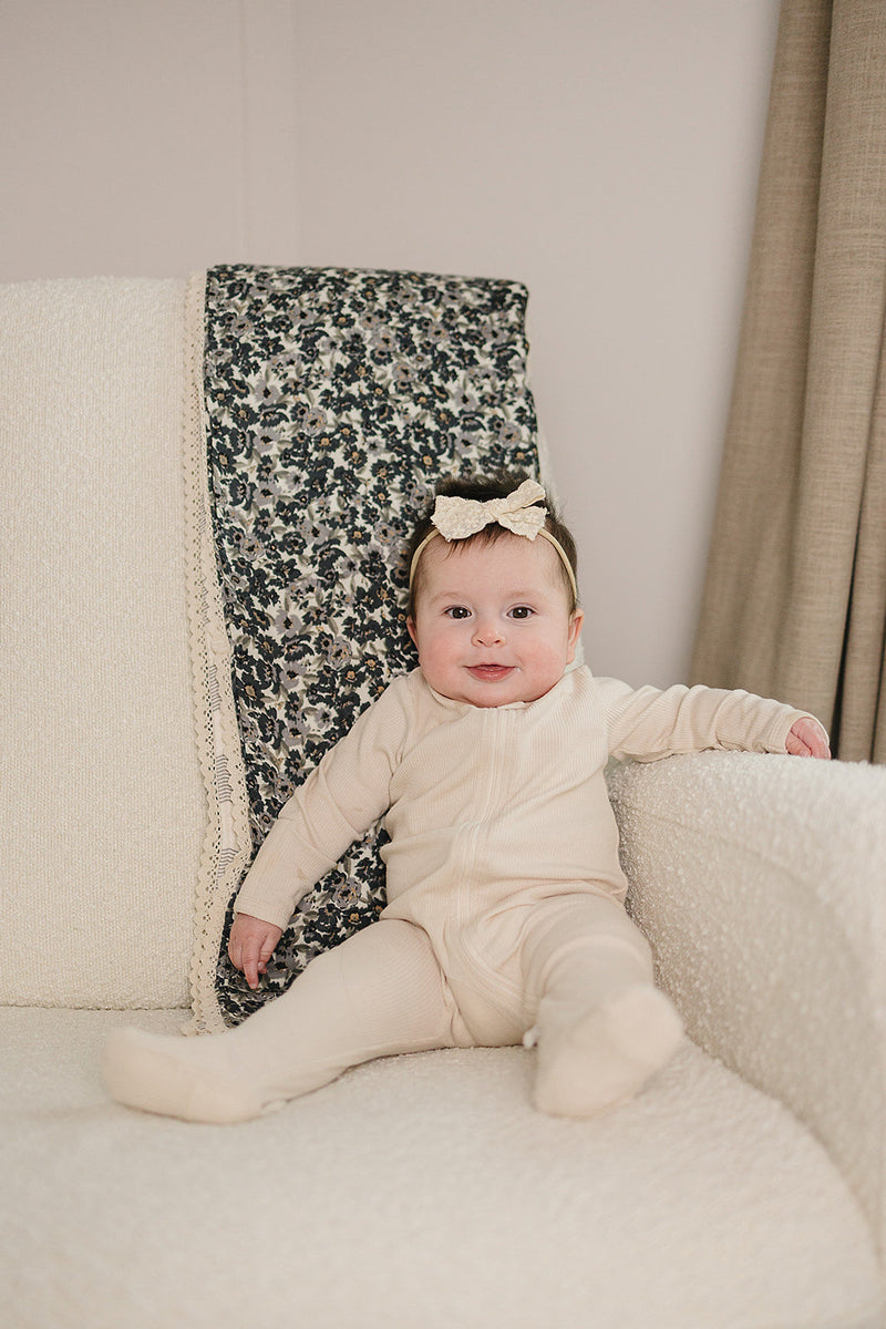 Draped across a nursery chair, this Mebie Baby quilt serves as a delicate muslin throw blanket for infants.