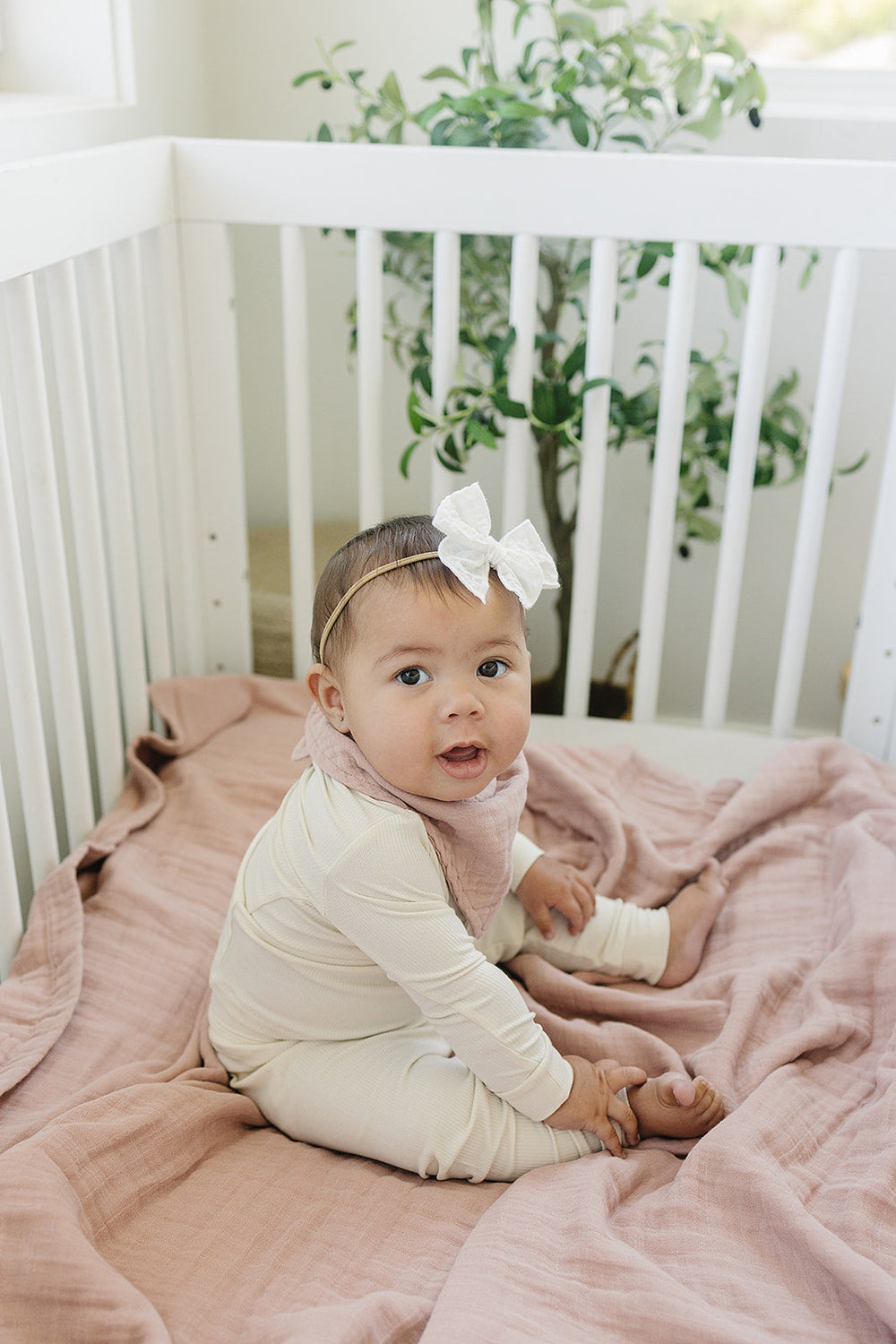 Draped in a nursery setting, the Mebie Baby Dusty Rose Muslin Quilt serves as a gentle muslin throw blanket.
