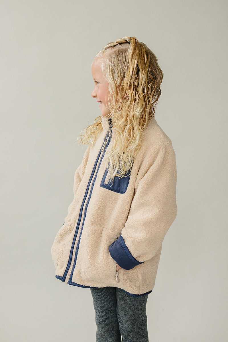 The Mebie Baby Sherpa Zip-Up Jacket features a soft texture, ideal for trendy baby clothes
