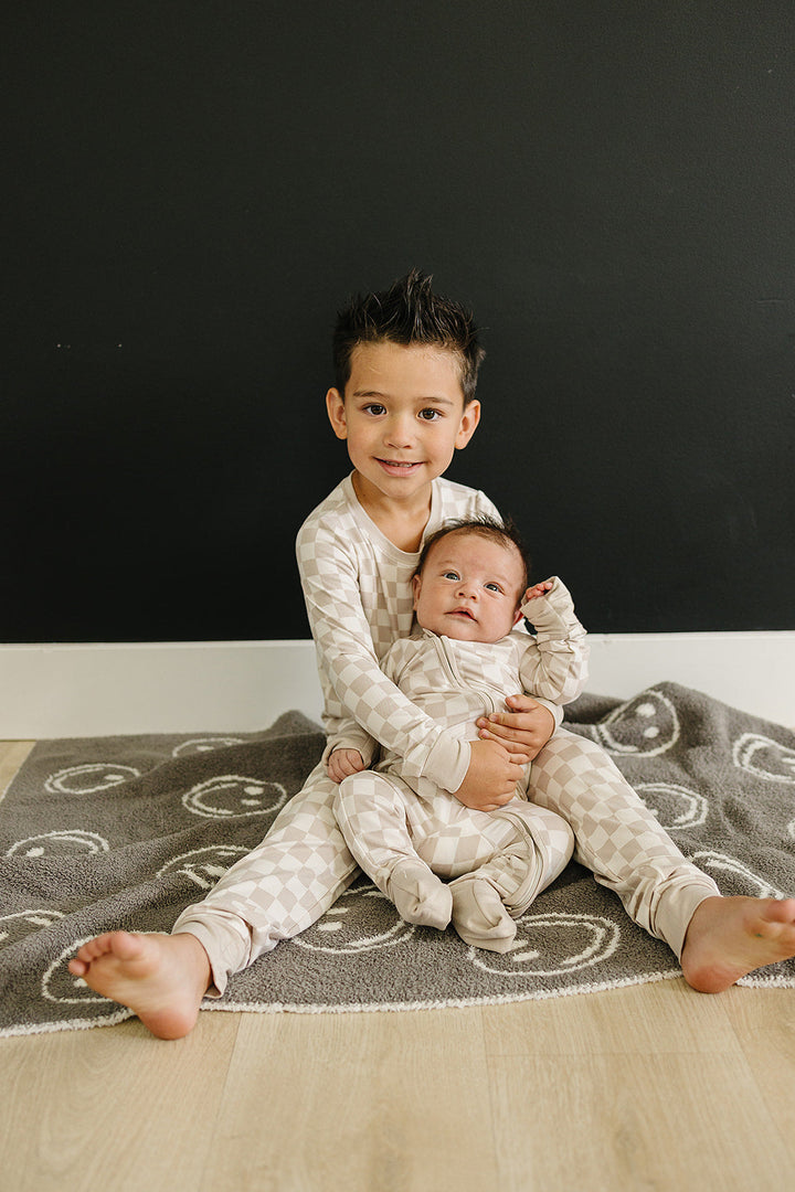 Candid lifestyle shot featuring the Mebie Baby Taupe Checkered Bamboo Zipper on a baby