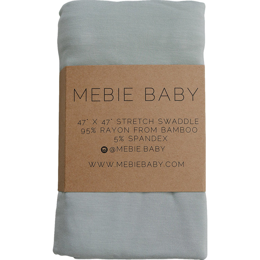 Sage Bamboo Stretch Swaddle by Mebie Baby, folded on a nursery shelf.