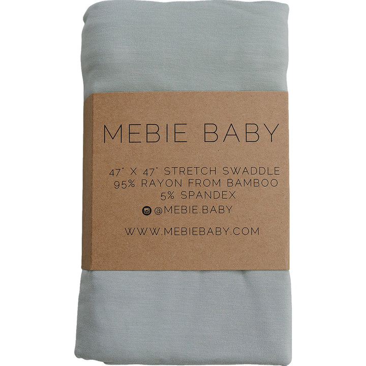 Sage Bamboo Stretch Swaddle by Mebie Baby, folded on a nursery shelf.