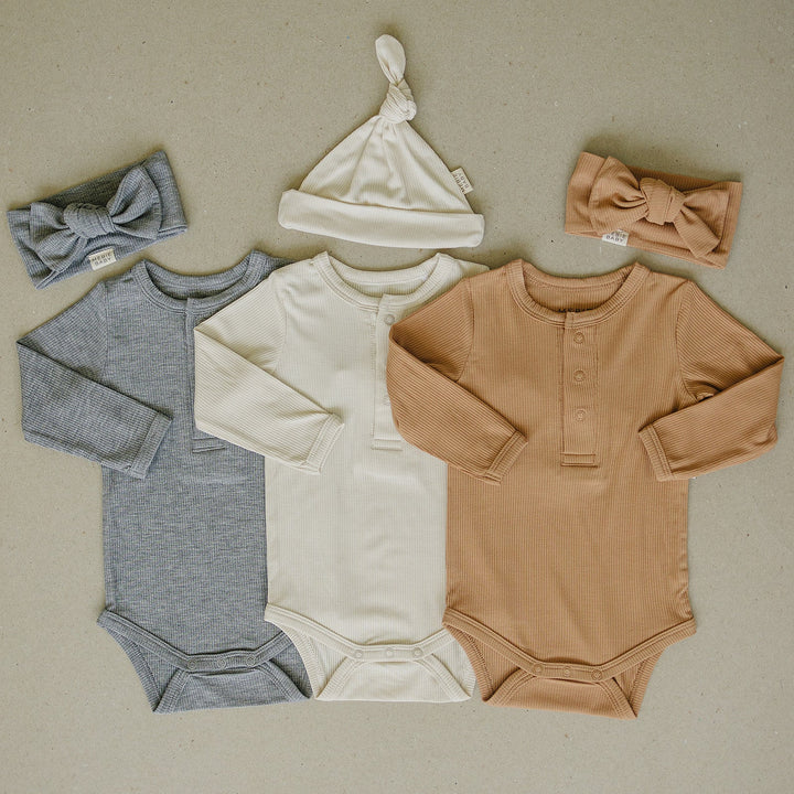Mebie Baby Latte Bamboo Snap Long Sleeve Ribbed Bodysuit pictured alongside coordinating baby accessories