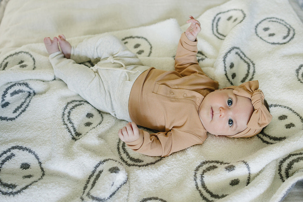 Close up detail shot of the Mebie Baby Latte Bamboo Snap Long Sleeve Ribbed Bodysuit fabric and stitching