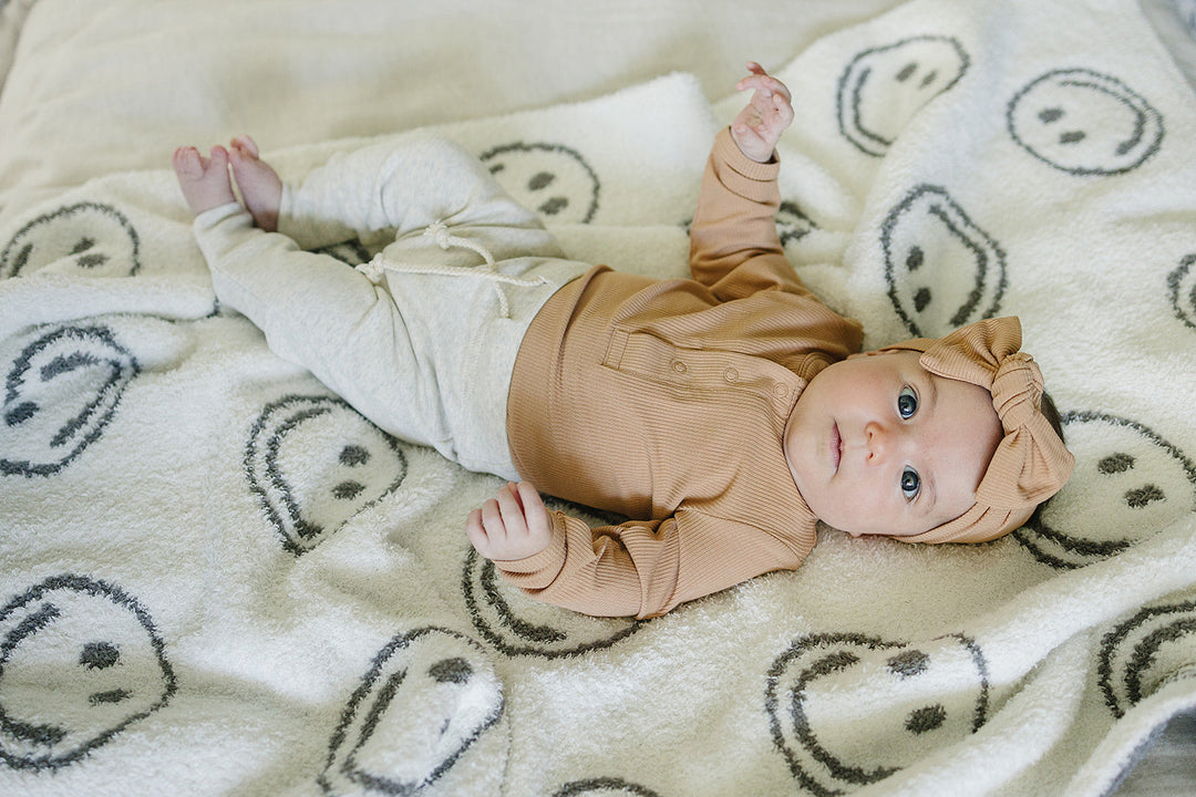 Close up detail shot of the Mebie Baby Latte Bamboo Snap Long Sleeve Ribbed Bodysuit fabric and stitching