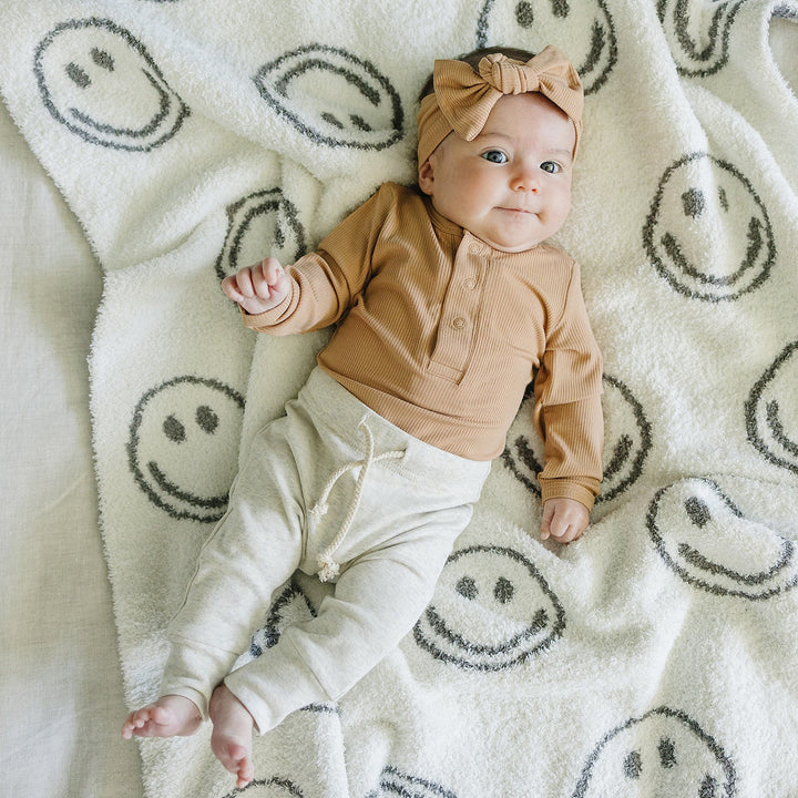 Latte Bamboo Snap Long Sleeve Ribbed Bodysuit displayed to show sizing and fit details of this ribbed baby bodysuit