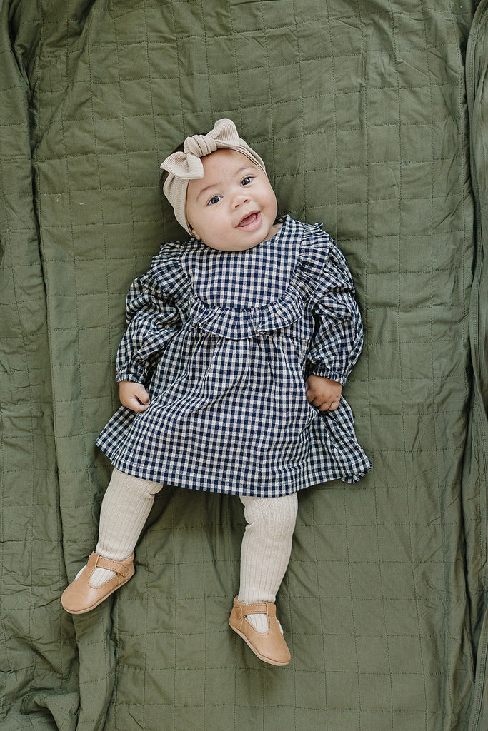 Baby laying in the Mebie Baby linen ruffle dress