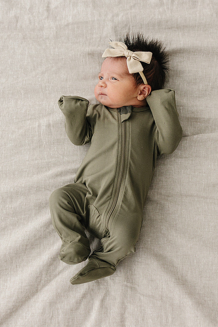 Baby modeling the Mebie Baby Olive Bamboo Footed Zipper, a soft bamboo footie pajama for everyday wear