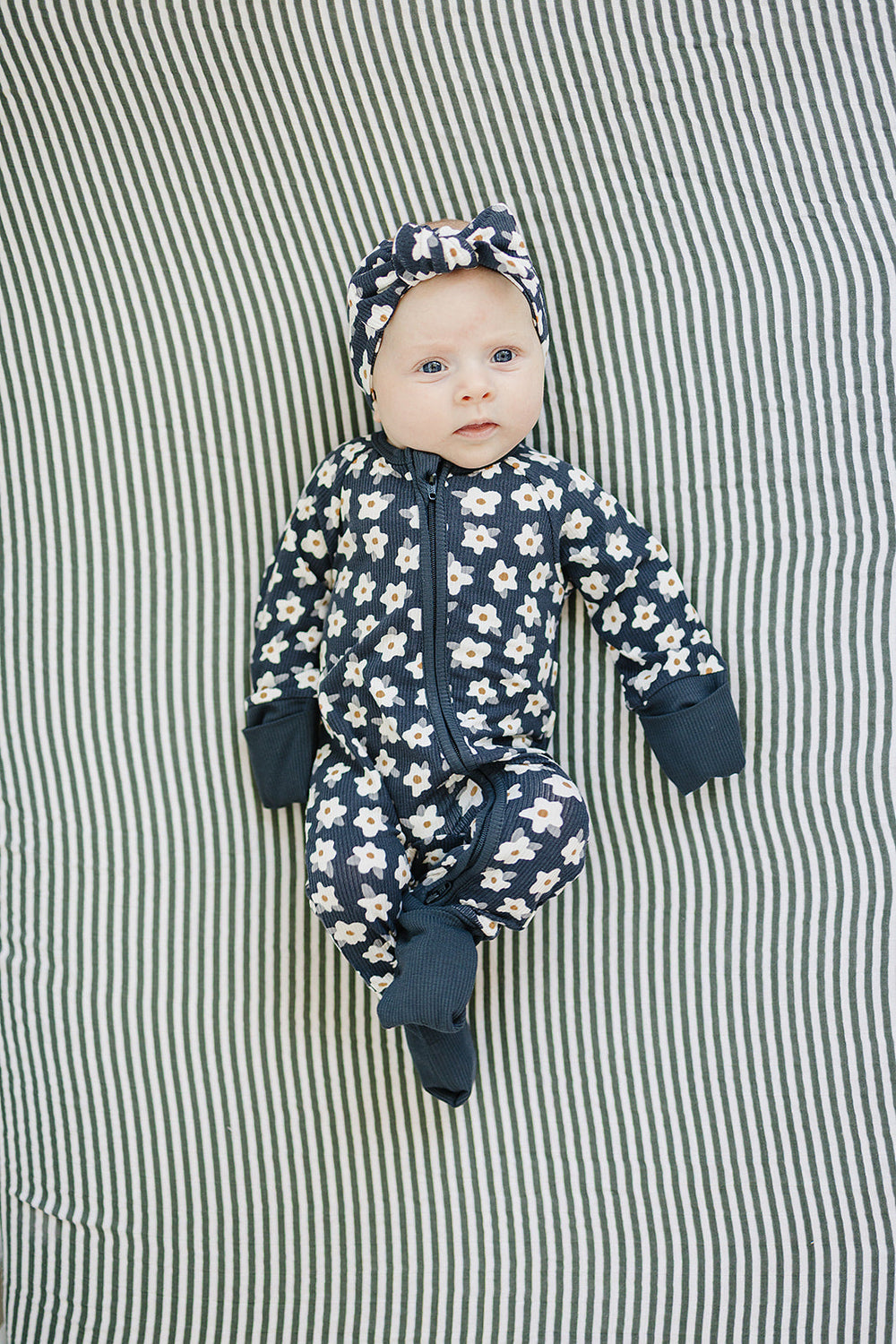Designed with a smooth zip closure, the Mebie Baby Navy Daisy Ribbed Bamboo Zipper works perfectly as cozy onesie pajamas