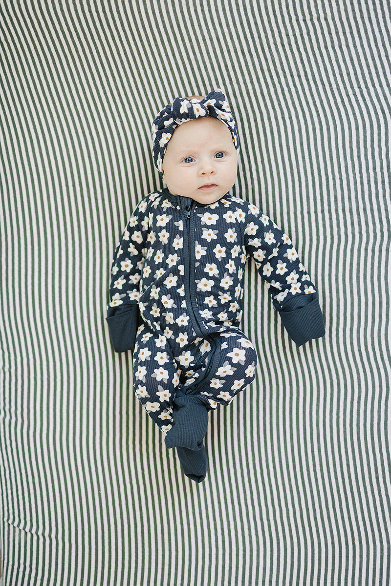 Designed with a smooth zip closure, the Mebie Baby Navy Daisy Ribbed Bamboo Zipper works perfectly as cozy onesie pajamas