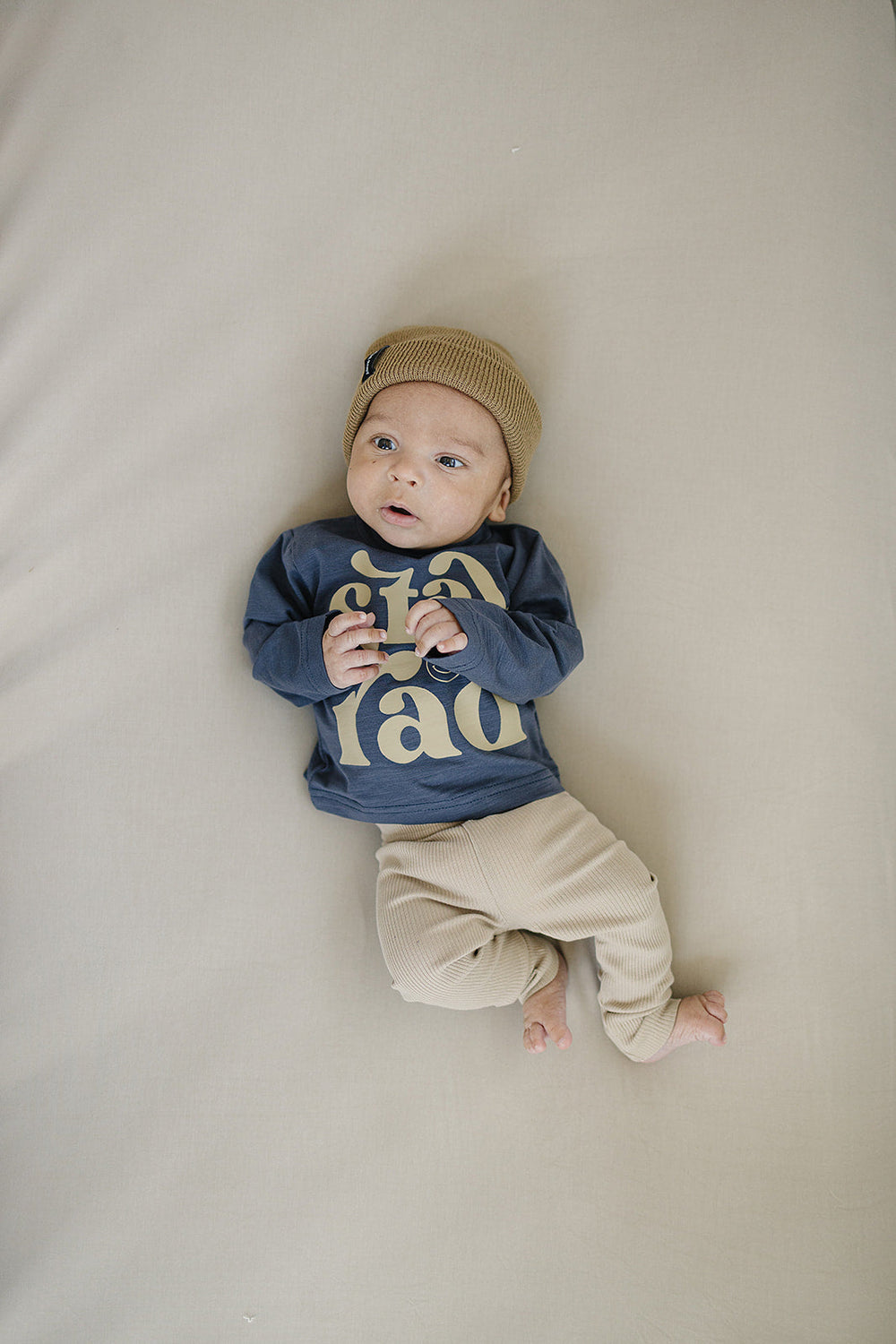Folded on a wooden shelf, the Oatmeal Organic Leggings from Mebie Baby.