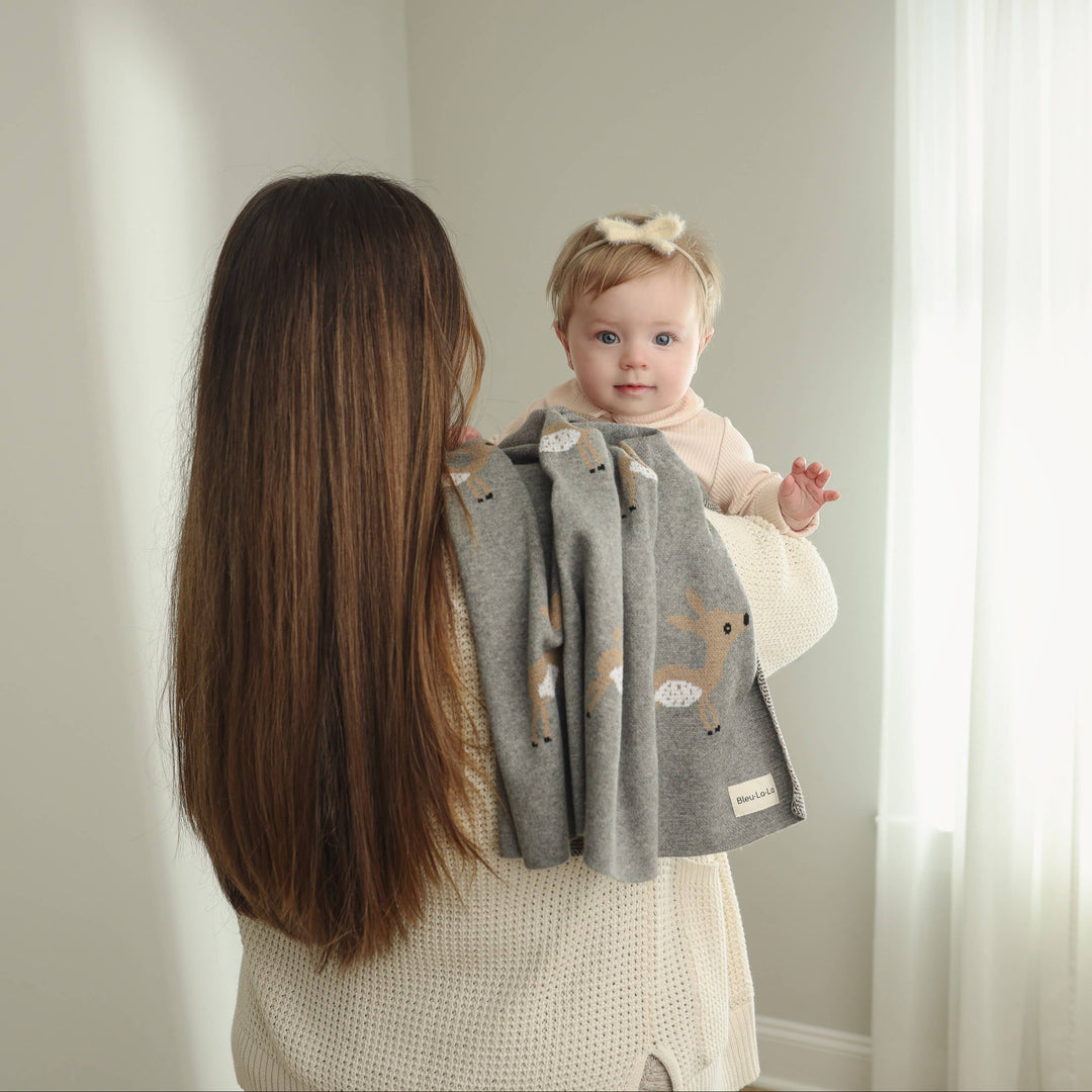 women holding infant and snuggling with green deer patterned bleu la la blanket 
