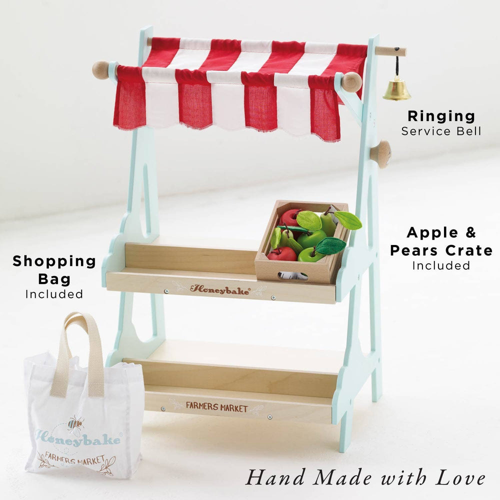 A striped canopy stall holds a crate of wooden pears and apples beside a folded cloth tote, Le Toy Van Market Stall