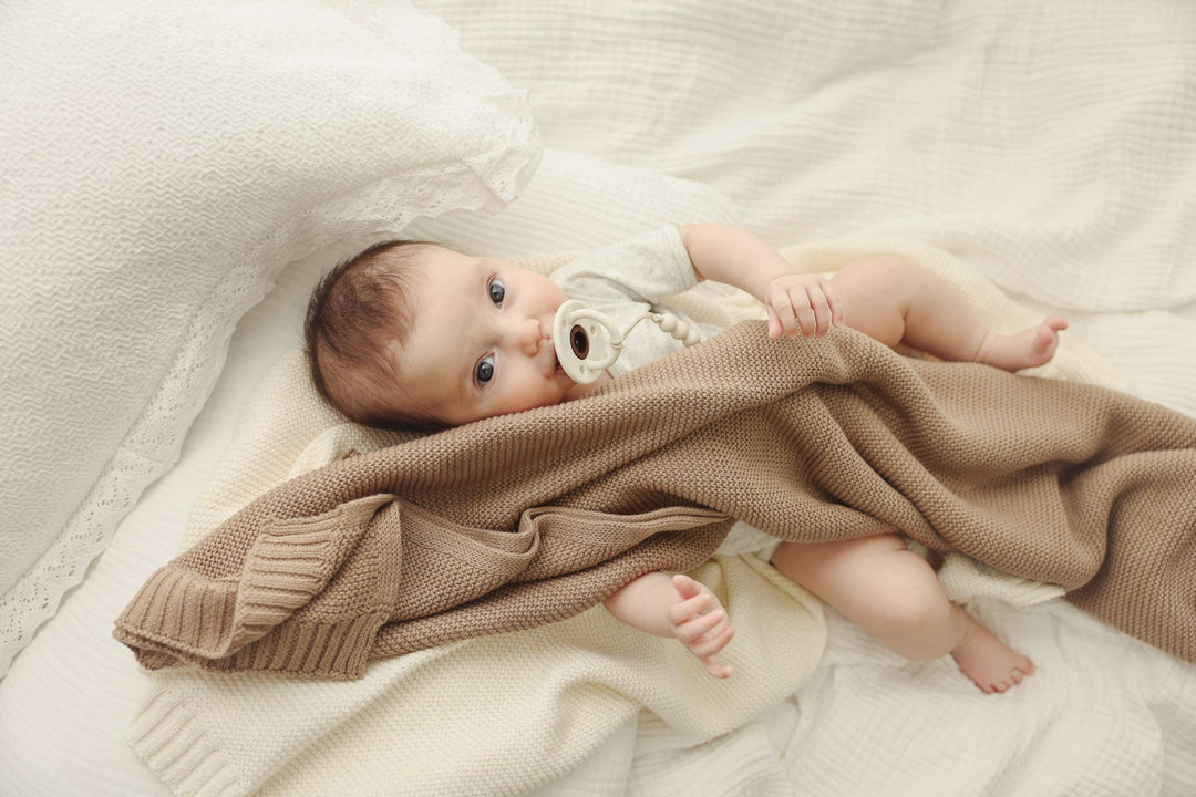 Baby lying on a soft surface with a Bleu La La Heritage Knit 100% Organic Cotton Swaddle Baby Blanket in Purple