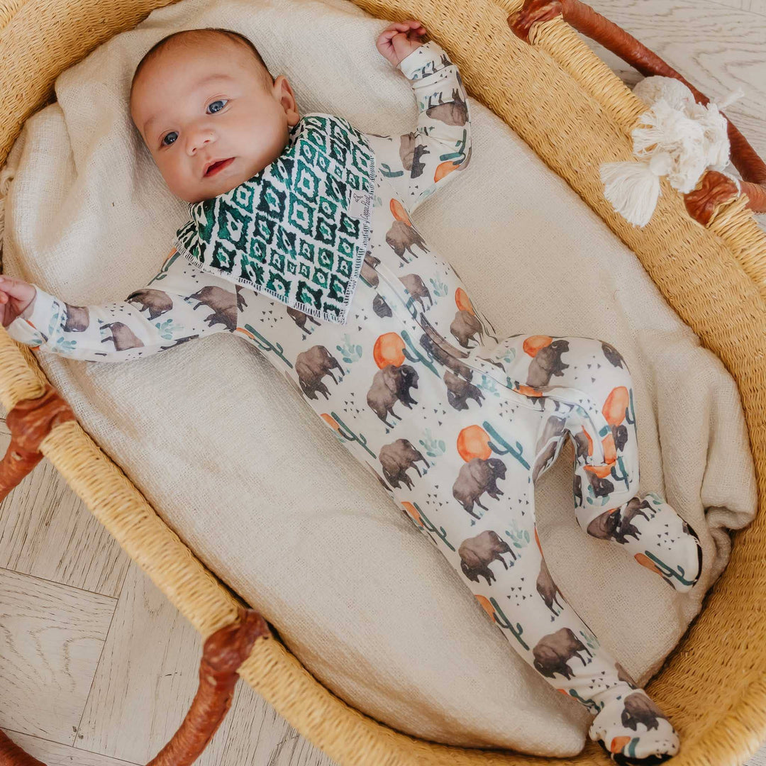 Baby wearing Copper Pearl Bison sleeper in bassinet, soft zip-up baby pajamas for newborn comfort and easy changes