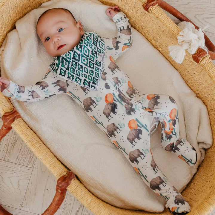 Baby wearing Copper Pearl Bison sleeper in bassinet, soft zip-up baby pajamas for newborn comfort and easy changes