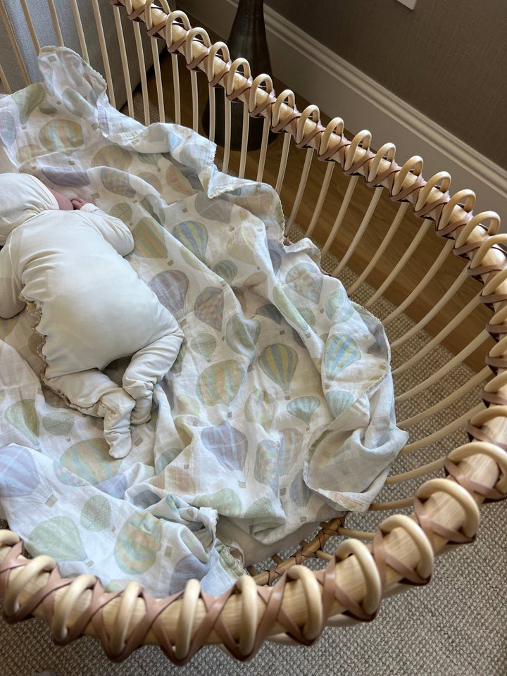 Little Threads muslin baby blanket styled in bassinet, breathable newborn bedding and organic cotton swaddle for supervised comfort