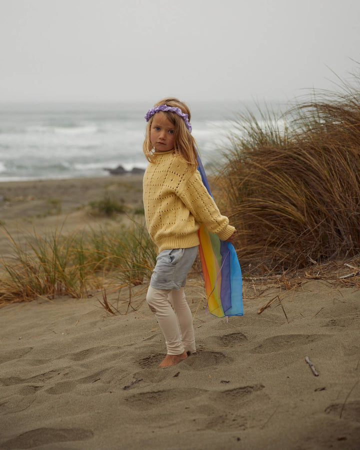 Sarah's Silks best selling children's toy, child in profile wearing the Rainbow Veil at the beach