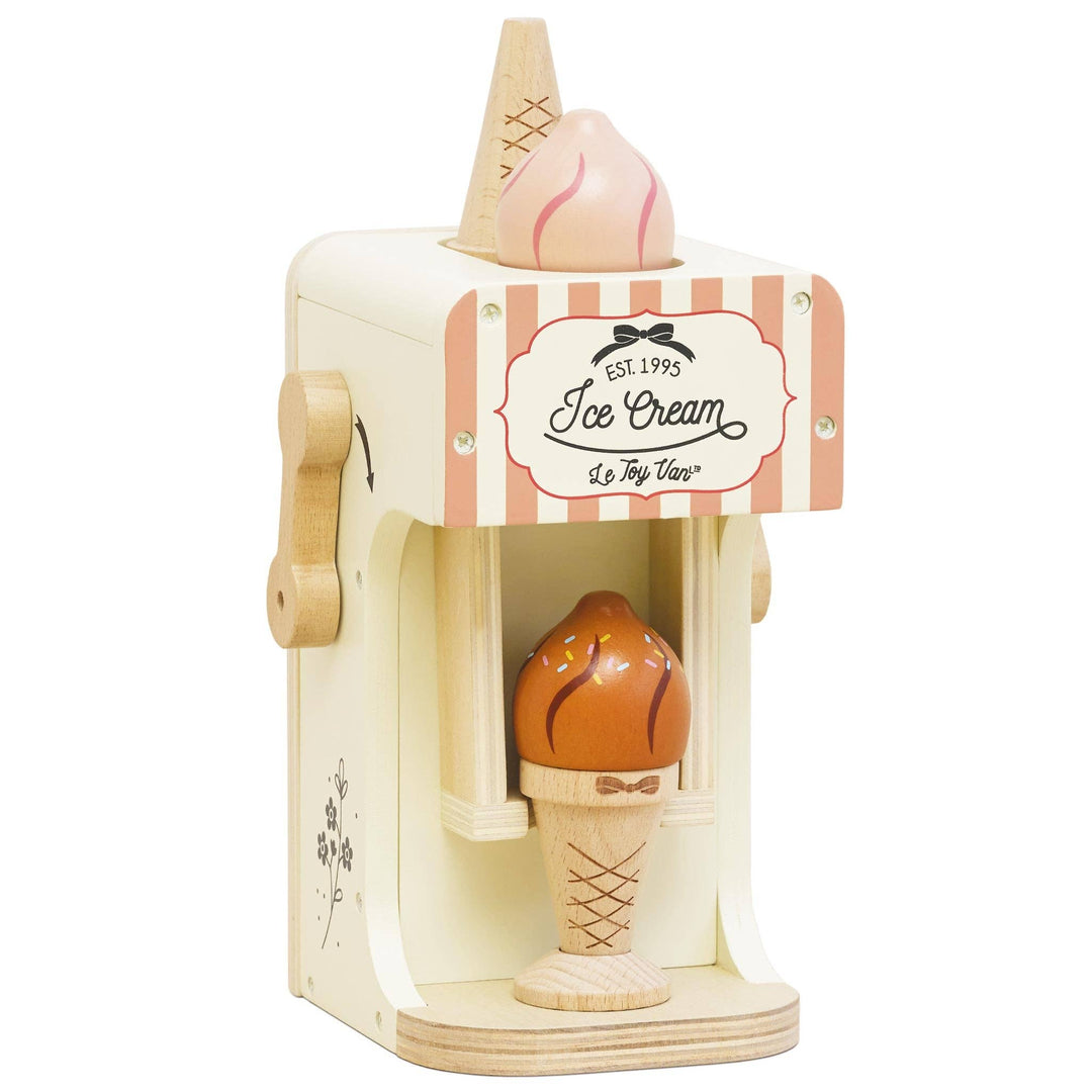 A cream colored ice cream machine with a pink striped awning and a chocolate swirl cone in Le Toy Van's set