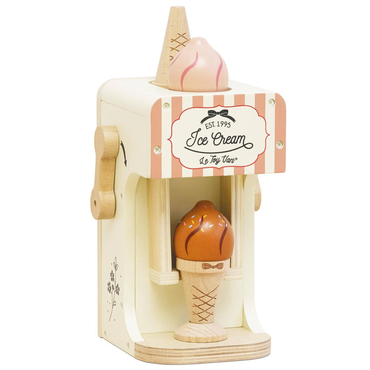 A cream colored ice cream machine with a pink striped awning and a chocolate swirl cone in Le Toy Van's set