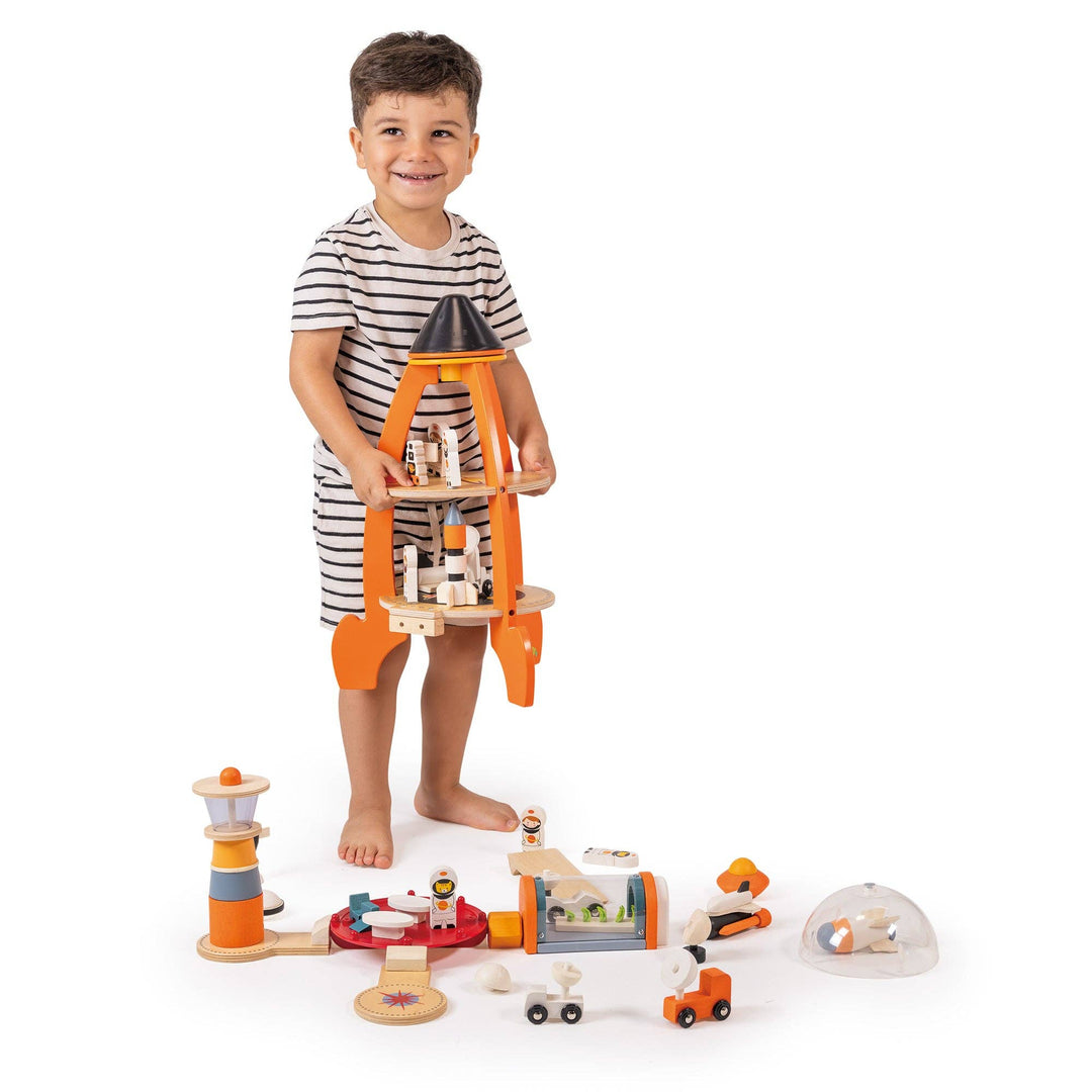 A barefoot toddler holds rocket pieces while exploring the Tender Leaf Toys Cosmic Rocket Set