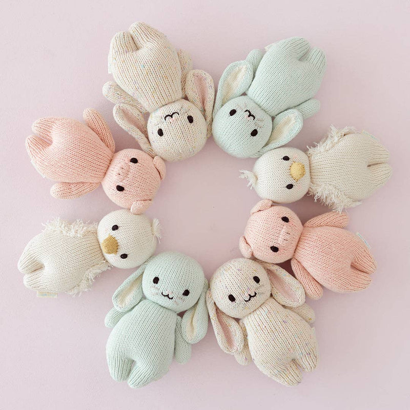 set of pastel colored hand knit cotton animals from cuddle + kind laying in circle