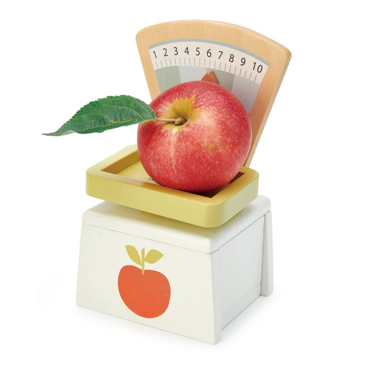 A wooden apple rests on the scale tray of the Tender Leaf Toys Market Scales set